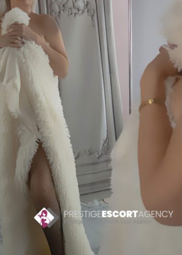 Woman in fur coat standing by mirror