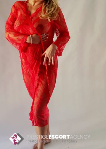 Woman in red lace dress poses confidently.